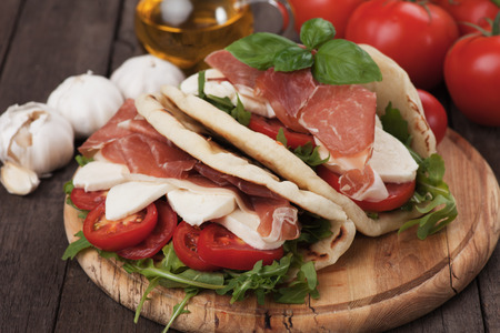 Piadina romagnola, italian flatbread sandwich with rocket salad, mozzarella cheese and prosciuttoの写真素材