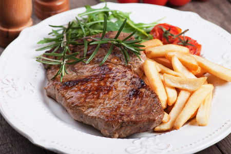 Beef rib-eye steak with french fries, rosemary and rocket saladの写真素材