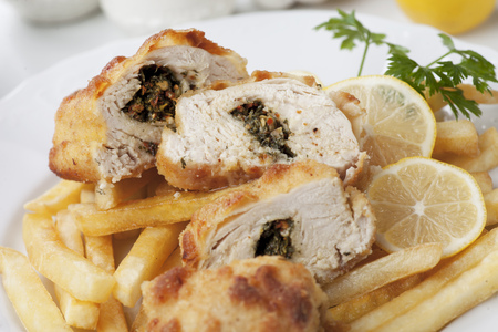 Breaded and stuffed chicken kiev with french fries and lemonの写真素材