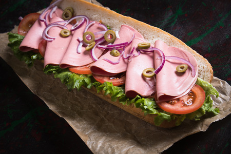 Italian submarine sandwich with cured meat, lettuce and tomatoの写真素材
