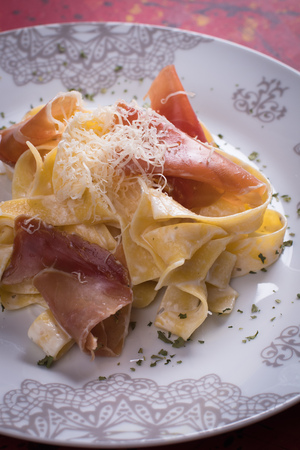 Italian pasta with cheese sauce and slices of prosciutto smoked hamの写真素材
