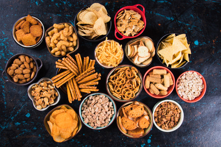 Salty snack including peanuts, potato chips and pretzels served as party food in bowlsの写真素材