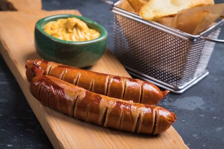 Grilled german sausaged with mustard and frued tomato chipsの写真素材