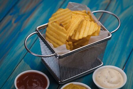 Thick ridge cut potato chips served in frying basketの写真素材