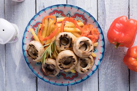 Grilled button mushroom caps with potato chips and vegetablesの写真素材