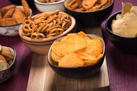 Salty snack including peanuts, potato chips and pretzels served as party food in bowlsの写真素材