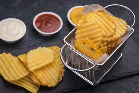 Thick ridge cut potato chips served in frying basketの写真素材