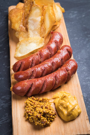 Grilled german sausaged with mustard and frued tomato chipsの写真素材