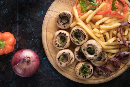 Grilled button mushroom caps with potato chips and vegetablesの写真素材