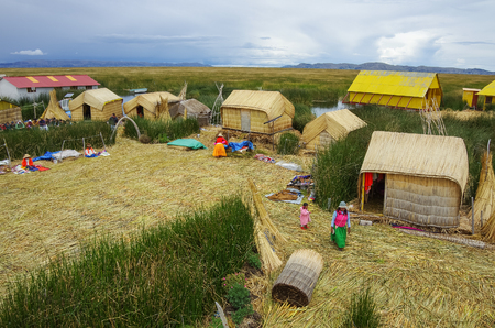 Titicaca, Peru, January 4, 2015 - Local people in traditional attires working near houses at Uros islands on Lake Titicaca.のeditorial素材