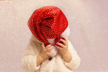 little boy in red santa hat playing and hiding his face. High quality photoの写真素材