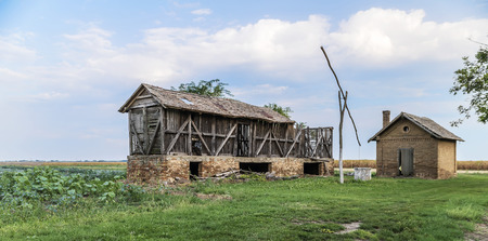 Old abandoned buildings and an old well in the summer fieldの写真素材