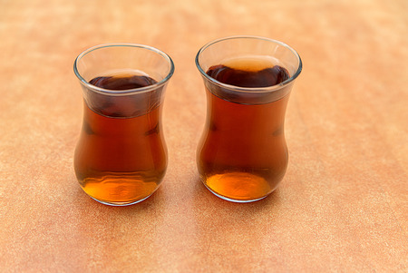 Two glass wine glasses filled with tea stand on the tableの写真素材
