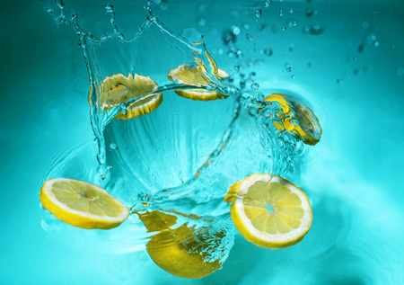 Juicy fresh yellow lemon slices in a blue whirlpoolの写真素材
