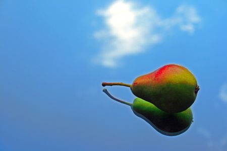 Pear on a mirror reflecting the blue skyの写真素材