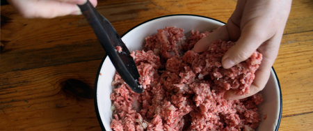 Women mixing raw mincemeat for raviolli