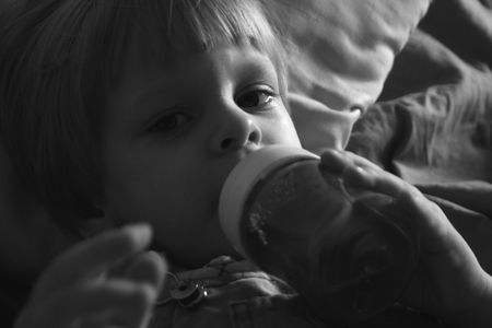 black and white portrait of a small boy drinking from a bottle with a nippleの写真素材