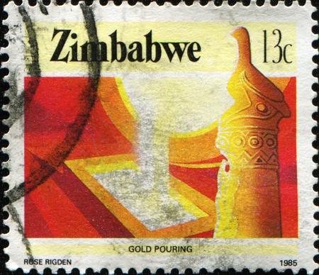 ZIMBABWE - CIRCA 1985: A stamp printed in Zimbabwe shows  gold being poured, series, circa 1985 の写真素材