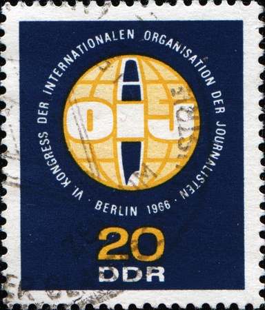GDR - CIRCA 1966: A stamp printed in Germany shows The International Organization of Journalists logo, circa 1966の写真素材
