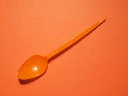 orange pastic spoons on orange backgroundの写真素材