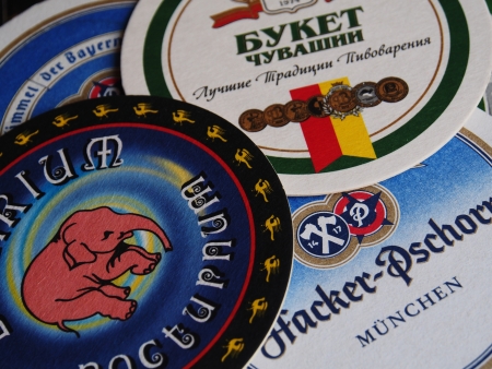 UKRAINE, LUGANSK - JANUARY 26, 2014: Modern beer mats.Beer lovers club meets monthly symbols in various pubs town. Men bring to meetings beer mats, labels and stoppers. They tasts new beers, discuss them and changing souvenirs.のeditorial素材