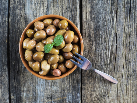 Green turkish olives in the bowl on the old wooden weathered tableの写真素材