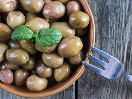 Green turkish olives in the bowl on the old wooden weathered tableの写真素材