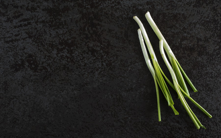 Top view of bunch of green onions on a black stone tableの写真素材