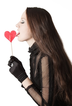 Pretty girl licking lollipop. Isolated over white.の写真素材