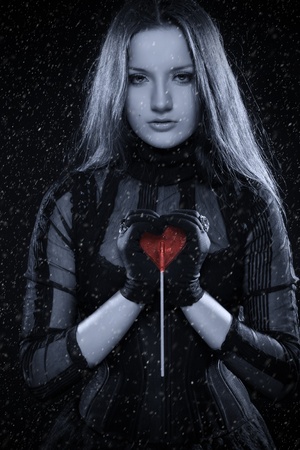 Cold gothic girl in corset with red sweet heart in her handsの写真素材