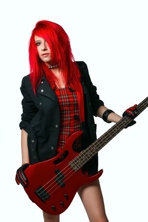 Redhead rocker girl in red dress with red bass guitar isolated over white の写真素材