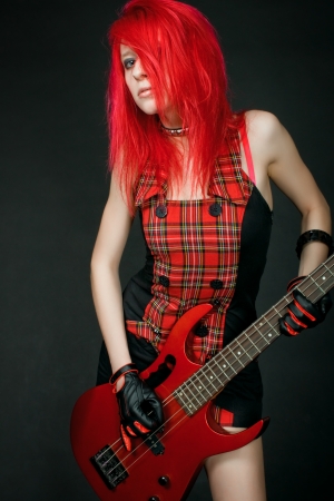 Redhead rocker girl with guitar posing over dark backgroundの写真素材