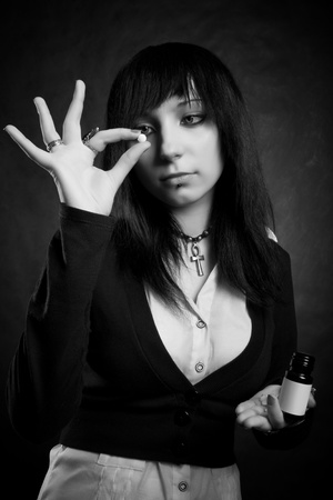 pretty gothic girl with pill posing over darkの写真素材