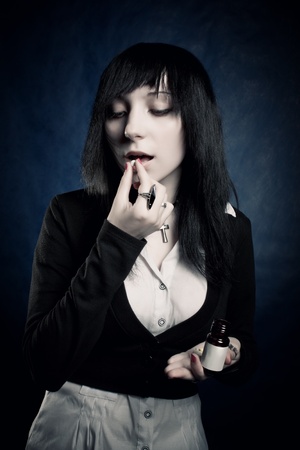 Pretty gothic girl eating tablet over blueの写真素材