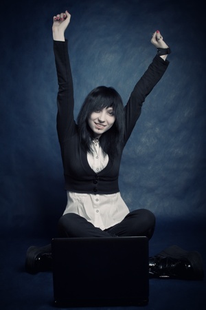 pretty gothic girl with laptop sitting over blue backgroundの写真素材