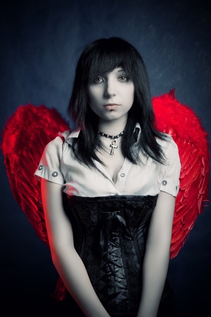 Prettty gothic girl with red wing posing over darkの写真素材