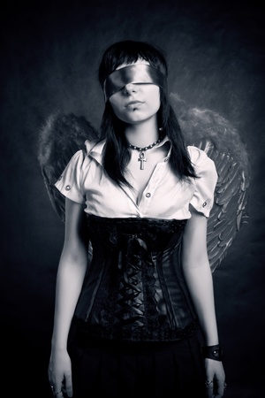 Pretty gothic girl with wings posing over darkの写真素材