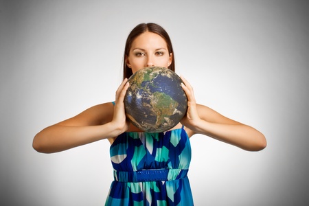 Pretty girl holding globe over whiteの写真素材