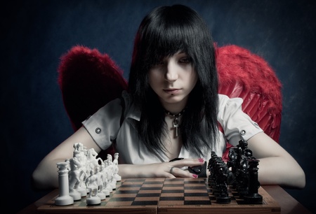 Pretty angel looking to chessboard over dark backgroundの写真素材