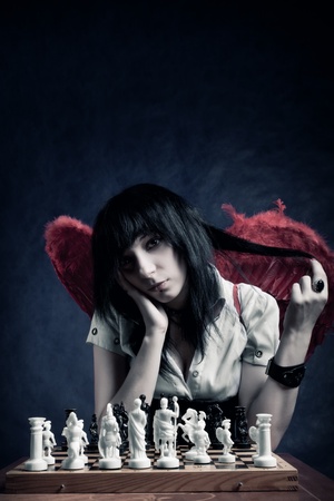 Pretty gothic girl with wings playing chessの写真素材