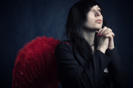 pretty gothic girl with red wings praying over darkの写真素材