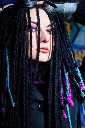 Pretty cyber girl with dreadlocks posing over wallの写真素材