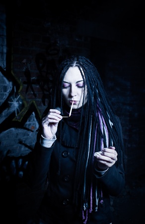 Cute girl smoking over wall with graffitiの写真素材