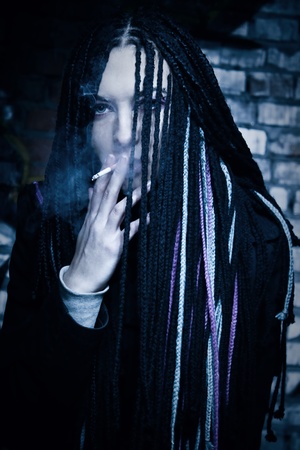 Cute girl smoking over wall with graffitiの写真素材