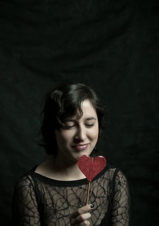 girl with heart-shaped lollipop posing over darkの写真素材
