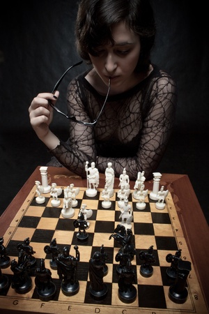 Pretty girl playing chess over dark backgroundの写真素材