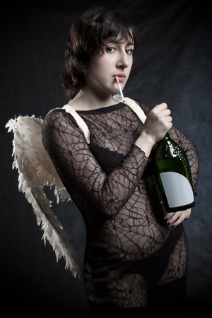 Pretty angel posing with cigarette and  bottle of wine over darkの写真素材