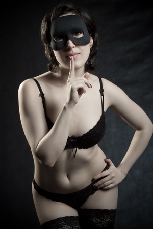 Pretty girl in mask posing over dark backgroundの写真素材