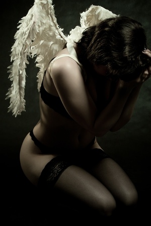 pretty angel posing over dark backgroundの写真素材