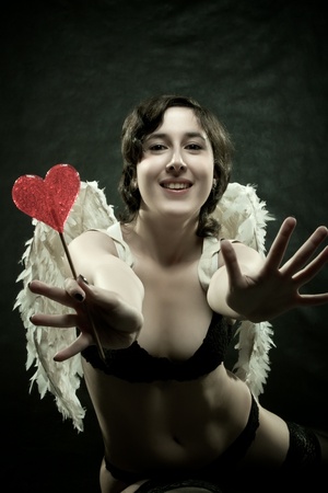 Pretty sexy angel with lollipop posing over dark backgroundの写真素材